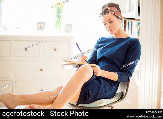 Woman Sitting on Chair Writing on Notebook