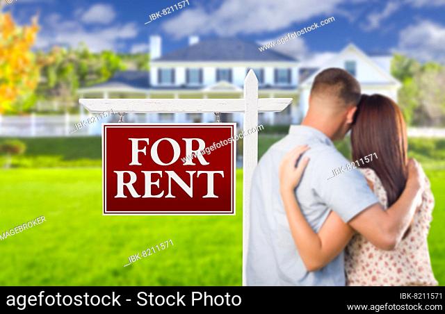 For rent real estate sign and affectionate military couple looking at nice new house