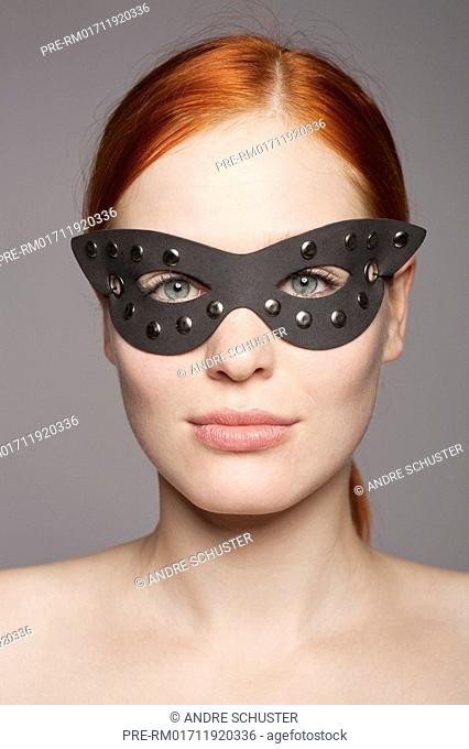 Young redhaired woman with dark mask