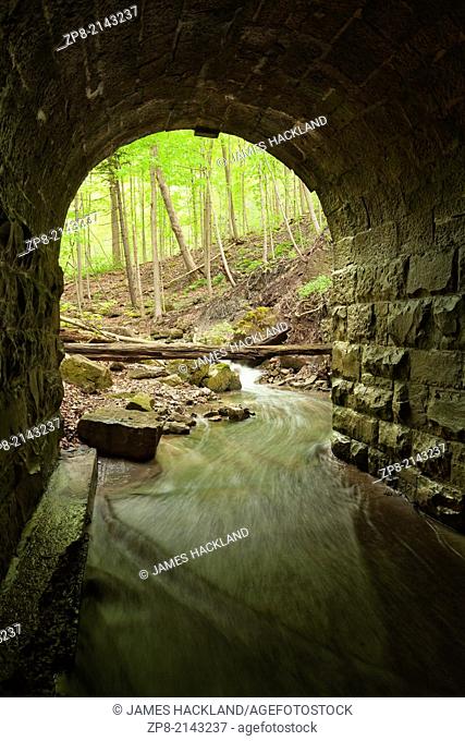 The entrance of a lovely stone block culvert looking out towards the forest in Tiffany Falls Conservation Area, Hamilton, Ontario, Canada
