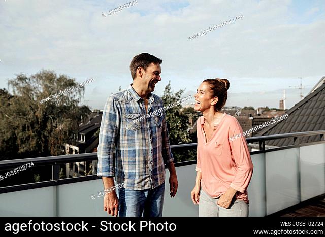 Cheerful mature couple laughing while standing in balcony