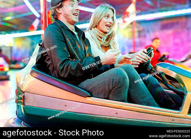 Young couple at fun fair riding bumper car