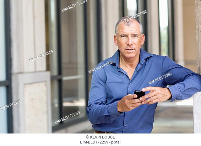 Caucasian businessman using cell phone in city