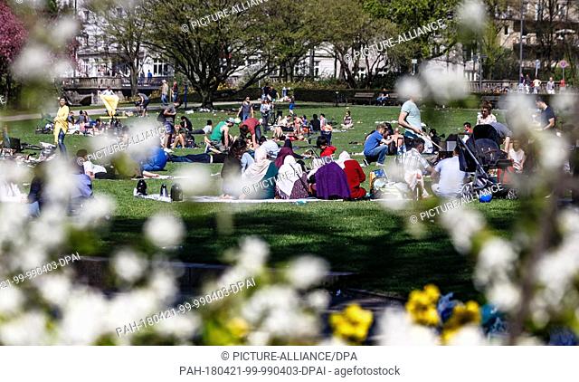dpatop - 21 April 2018, Germany, Hamburg: People enjoy the sunshine and warm temperatures at the Schwanenwik park on the Aussenalster river