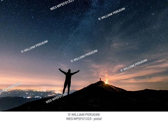 Italy, Monte Nerone, silhouette of a man looking at night sky with stars and milky way