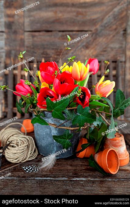 Buntes Bouquet mit frischen Tulpen in rustikalem Blumentopf