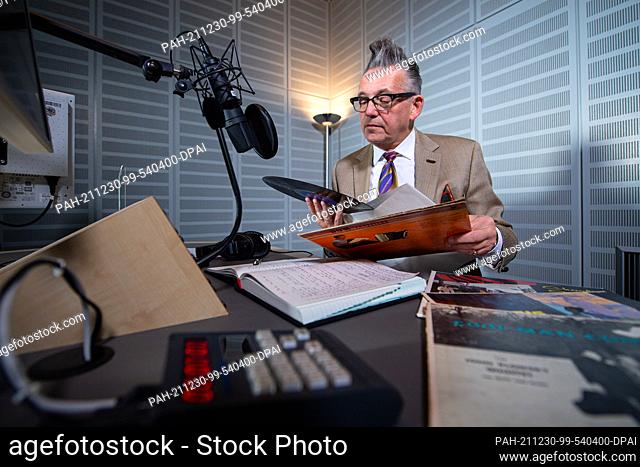 PRODUCTION - 21 December 2021, North Rhine-Westphalia, Münster: Götz Alsmann sits in the recording studio at WDR radio in Münster and holds a record in his...