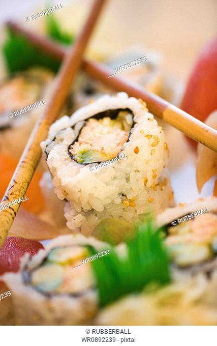 Close-up of sushi rolls with chopsticks