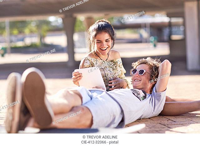 Teenage couple hanging out using digital tablet