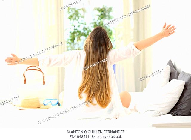 Back view portrait of an excited woman celebrating summer vacations in an hotel room