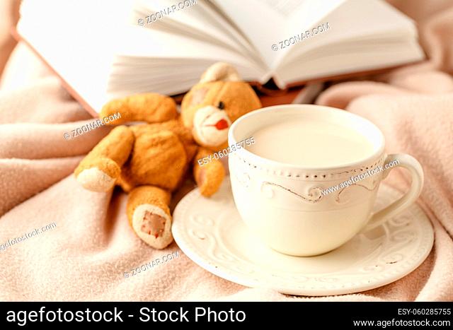Cup of tea with autumn leaves reflection on book on wooden table. Season of Education