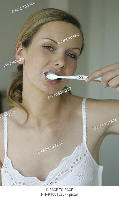 A blonde woman brushing her teeth