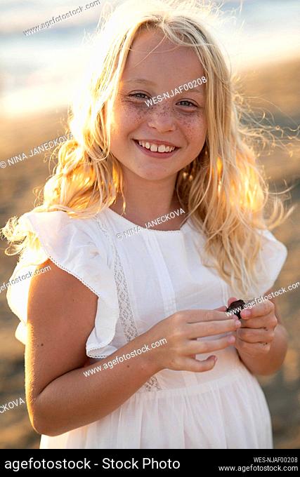 Happy blond girl with freckle on face at beach