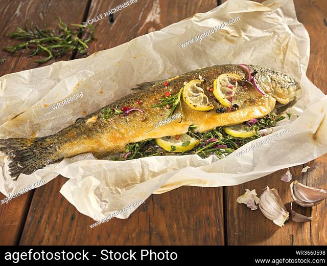 Fried trout stuffed with herbs on wooden plank