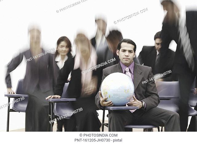 Portrait of a businessman sitting in a meeting holding a globe