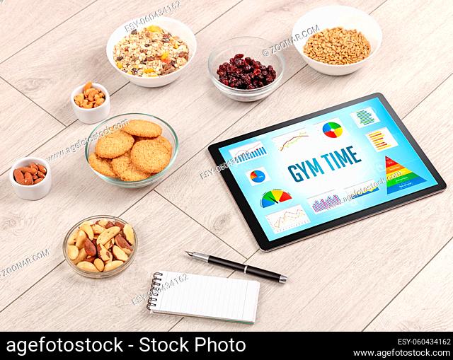 Organic food and tablet pc showing GYM TIME inscription, healthy nutrition composition