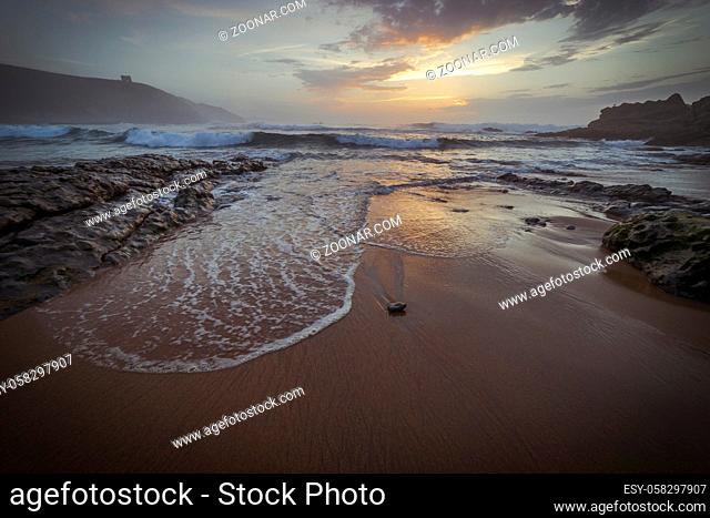 Calm, Sunset in Tagle beach. panoramic view of nice colorful huge cliff and sea on the back. Cantabria. Spain
