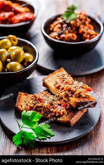 Crispy crostini with tapenade and ingredients. Tapenade - delicious olive paste from France