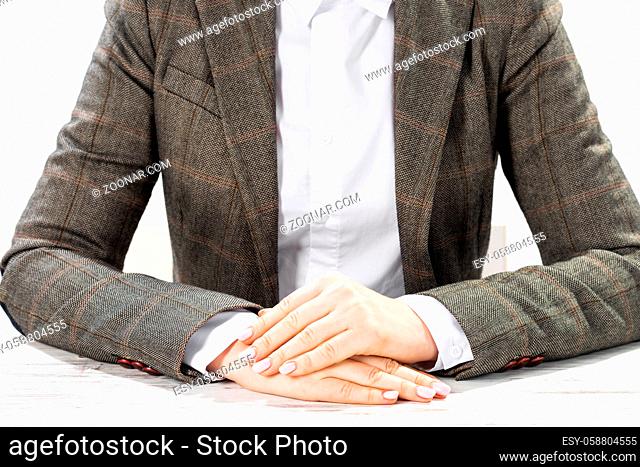 Close up businesswoman sitting at desk with folded arms. Concentrated business lady on background of white wall. Business consultation in office