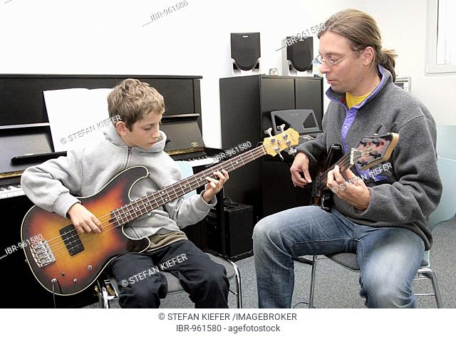Youth, 15, with his music teacher during a music lesson with a bass guitar in a private music school, Music Academy in Regensburg, Bavaria, Germany, Europe