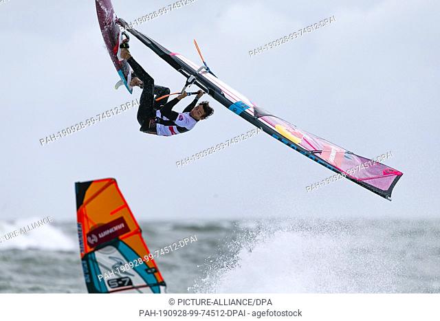 28 September 2019, Schleswig-Holstein, Westerland: Arthur Arutkin from France jumps during a competition. The best windsurfers of the world meet from 27