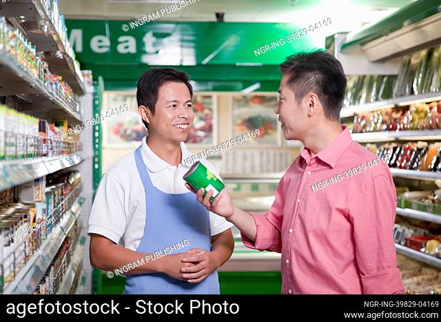 Sales clerk assisting man in supermarket, Beijing