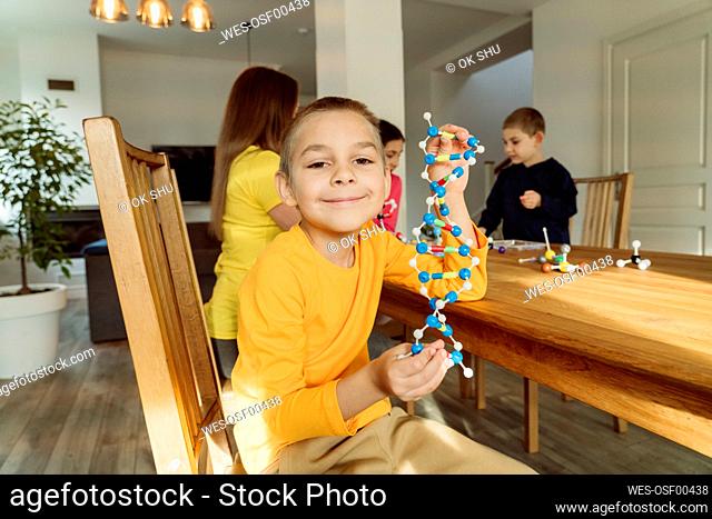 Boy with DNA model at table by family at home
