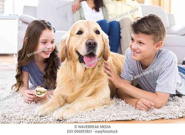 Siblings lying with dog while parents sitting on sofa