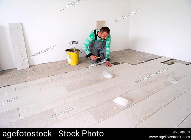 skilled worker installing the ceramic wood effect tiles on the floor Worker making laminate flooring on the construction site of the new apartment