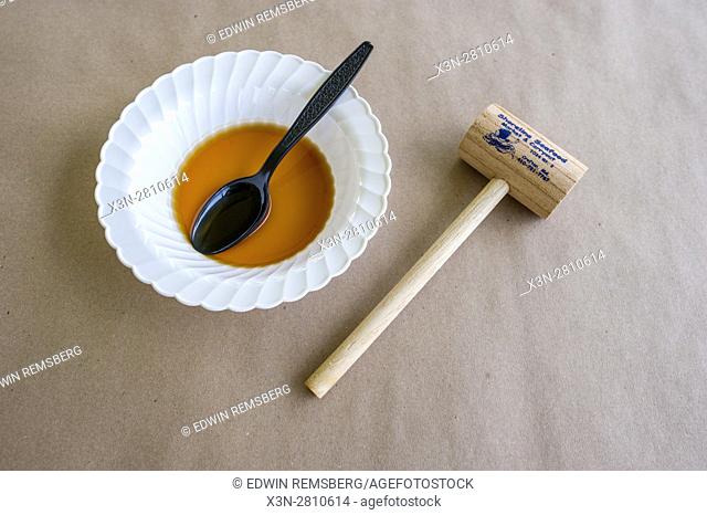 A helping of crab soup next to a crab mallet on a picnic table