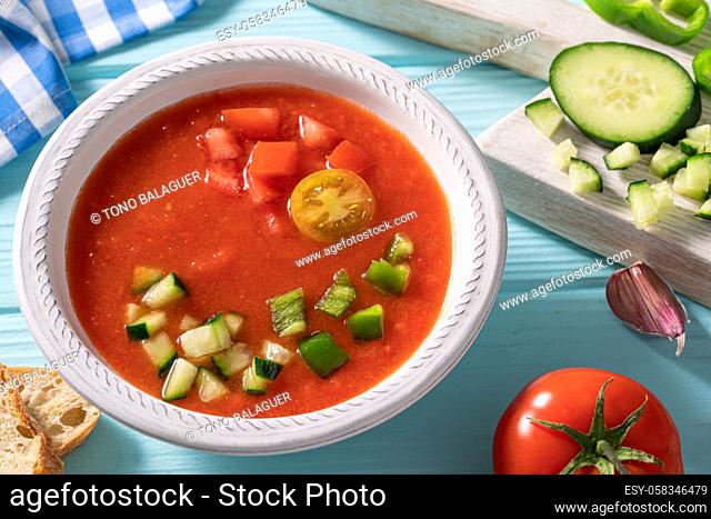 Gazpacho Andaluz is an Andalusian tomato cold soup from Spain with cucumber, garlic, pepper on light blue background