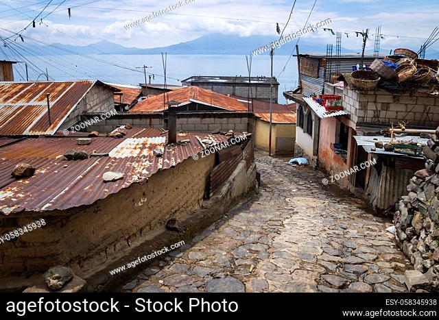 Street along local houses with rusty tin roofs in steep mountain village along lake Atitlan, Santa Cruz la Laguna, Guatemala
