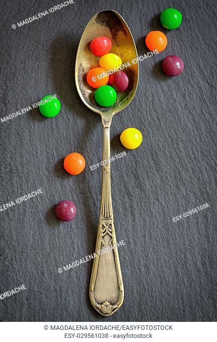 Colorful jelly candies in spoon on ardesia plate