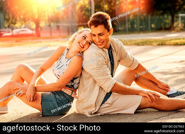 happy couple sitting on basketball playground