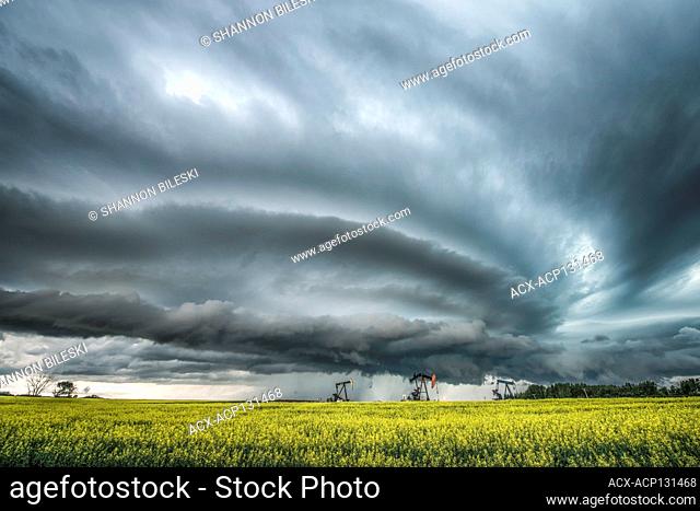 Storm with mesocyclone over a canola field with oil pumps in southern Saskatchewan Canada