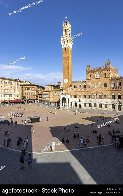 Siena, Siena Province, Tuscany, Italy. The Palazzo Pubblico with the Torre de Mangia seen across the Piazza del Campo. The historic centre of Siena is a UNESCO...