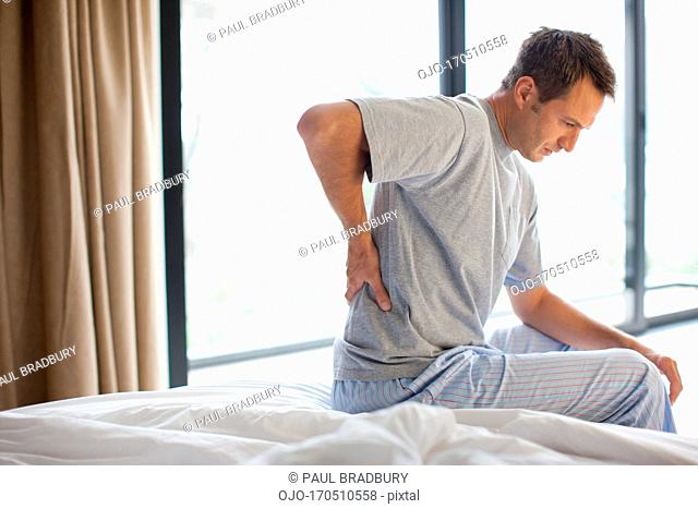 Man sitting on bed with backache