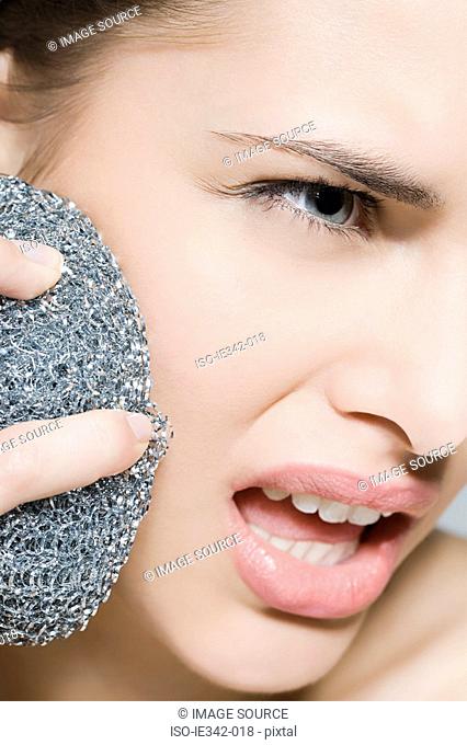 Woman using scouring pad on her face