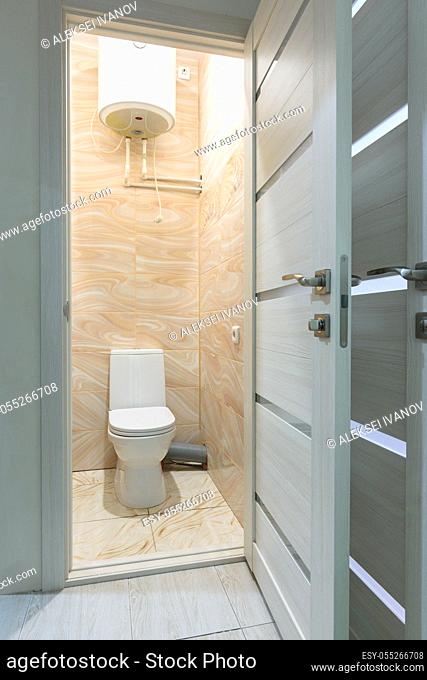Open door to a small toilet, a water heater is located upstairs