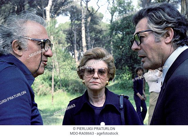 Italian actor Marcello Mastroianni and Italian director Federico Fellini talking on the set of La città delle donne, under the gaze of Italian actress Giulietta...