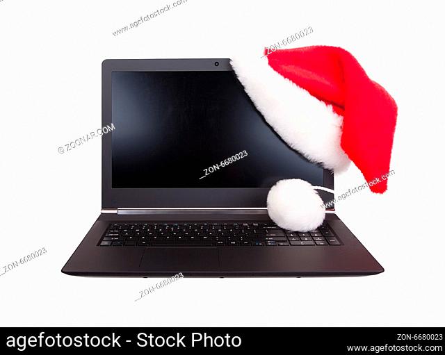 Modern open laptop with red santa claus hat put on lcd corner, isolated on white