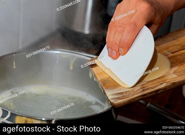 Making Spaetzle, a traditional south german specialty food made of lumps of dough by scraping the dough over a wooden board into hot water