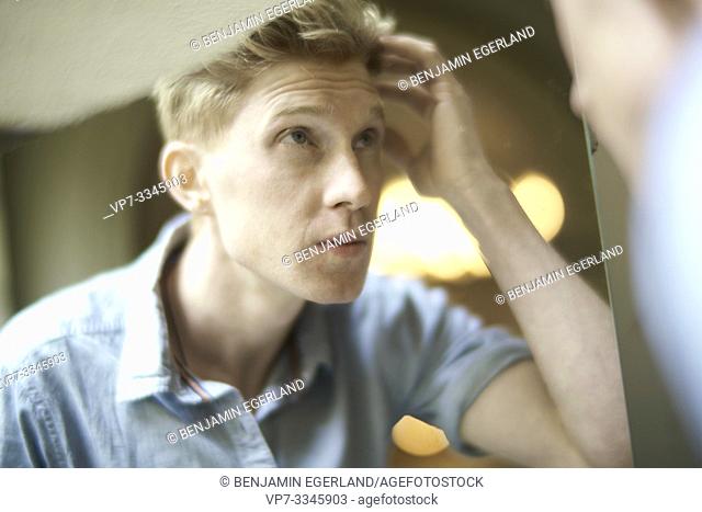young man checking his appearance in mirror