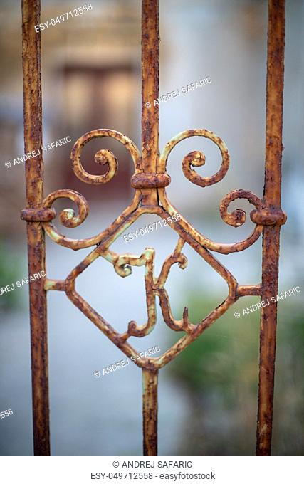 Old rusty iron gate with letter K, abandoned house in background, rustic home decor, vintage blacksmith design