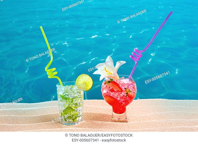 Mojito and strawberry cocktails on white sand beach and turquoise sea