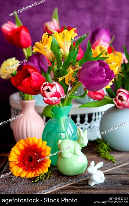 Bunte Fruehlingsblumen in kleinen Vasen mit Dekoration zu Ostern