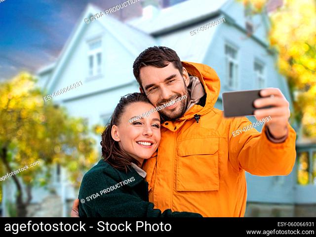 couple taking selfie over house in autumn
