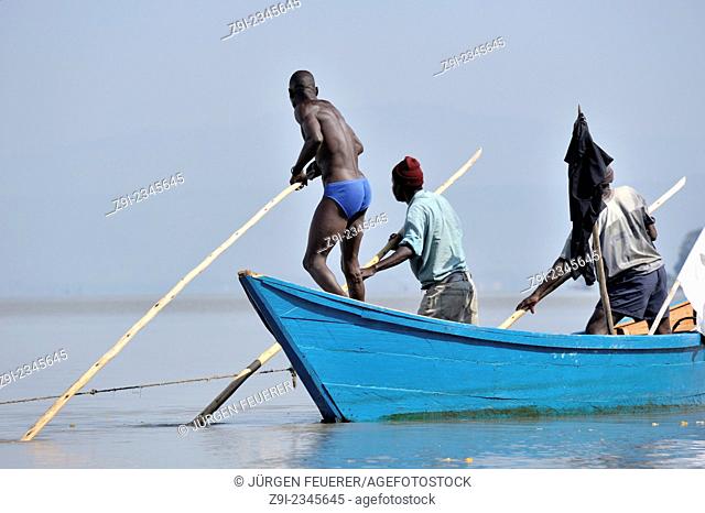 Fishers pushing their boat through the water at Lake Victoria, Kenya