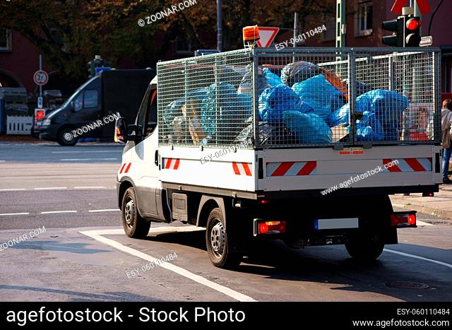 Ein kleiner Transporter mit vergitterter Aufladefläche transportiert Müllsäcke