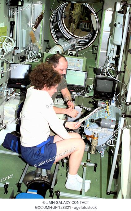 Susan J. Helms, flight engineer, and Yury V. Usachev of Rosaviakosmos, mission commander, read over procedures at the computer workstation in the Zvezda Service...